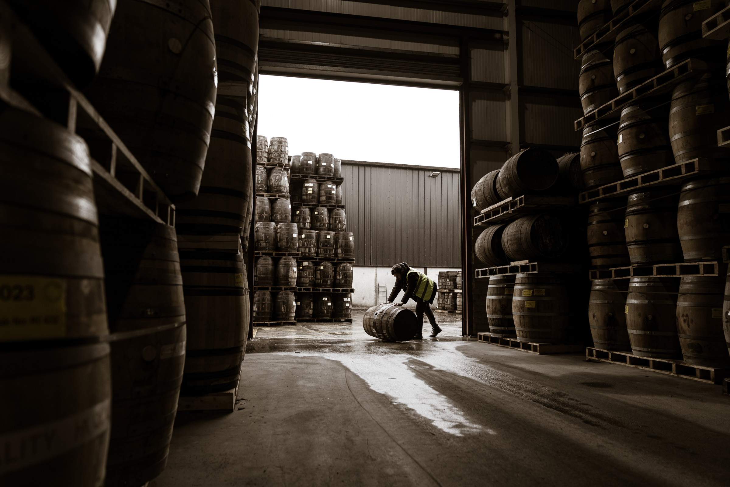 A West Cork Distillers team member rolling a cask through the warehouse doorway